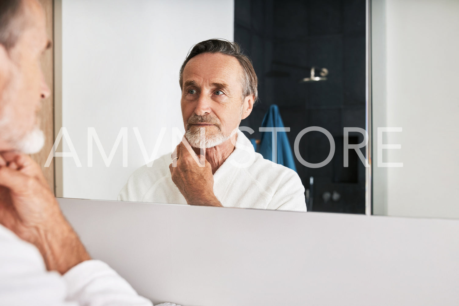 Handsome male in bathrobe inspecting his skin at morning