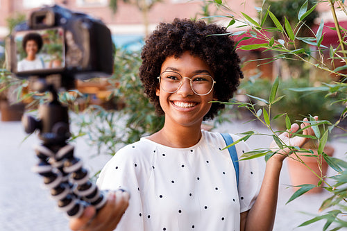 Blogger recording video from vacation. Smiling woman holding a digital camera on tripod.