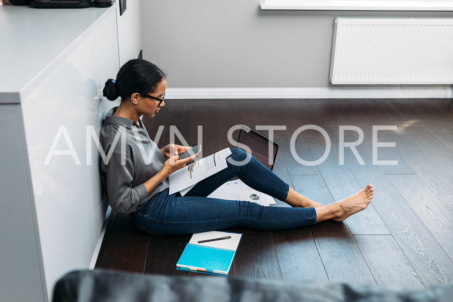 Side view of female using mobile phone while sitting on floor at home	