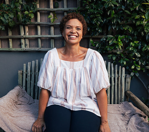 Happy mature woman on a bench. Middle age female with short hair laughing outdoors.