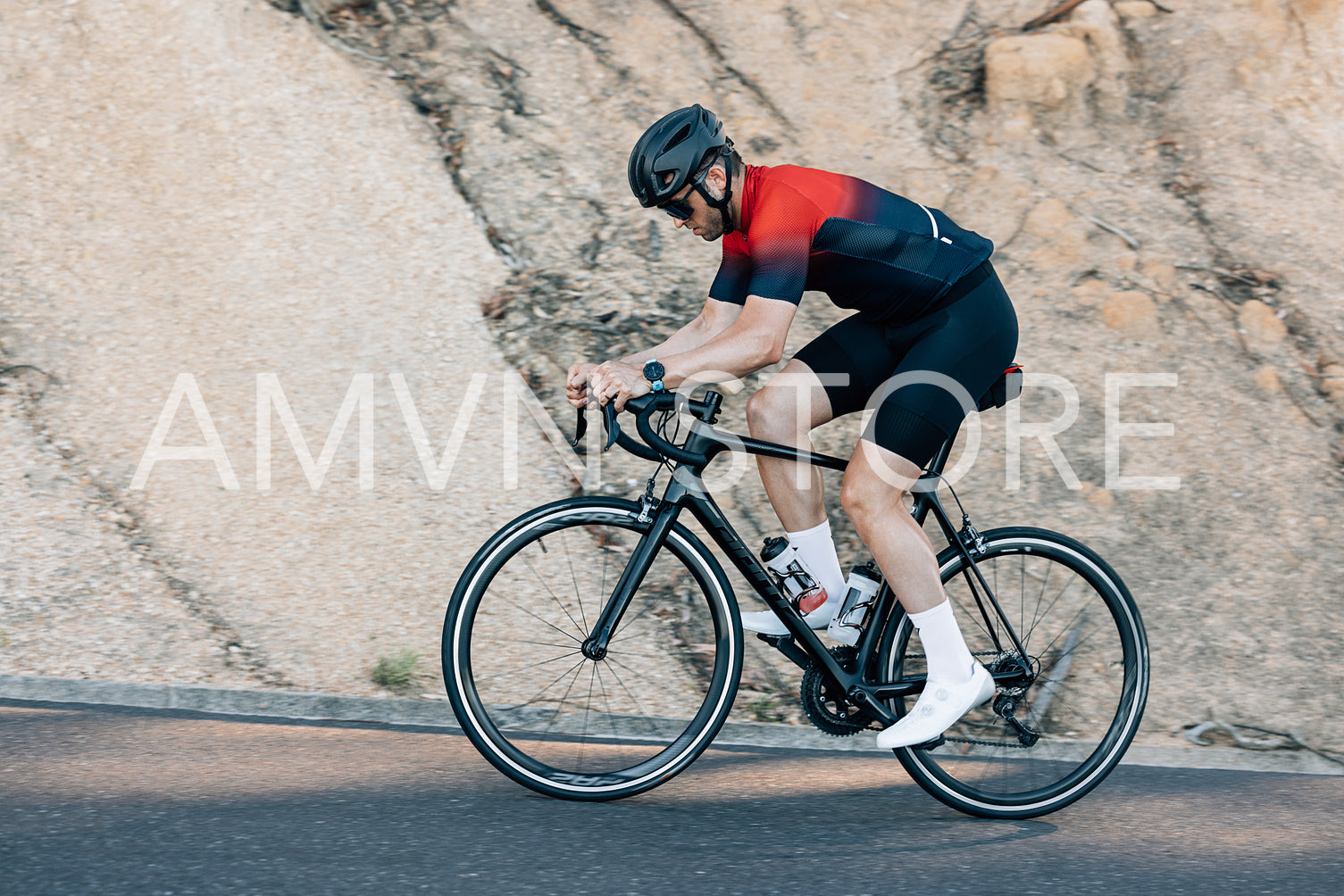 Male cyclist riding up on a road. Professional cyclist in sportswear doing intense training outdoors.