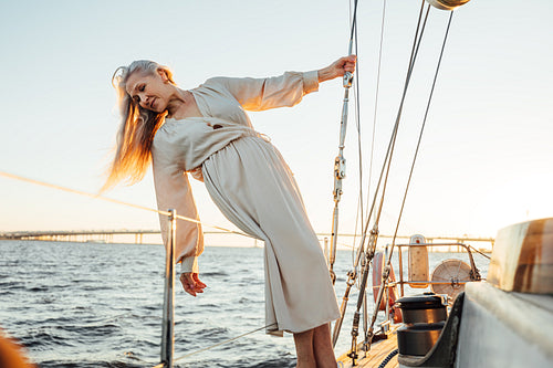 Beautiful senior woman with long hair posing on yacht and looking on water