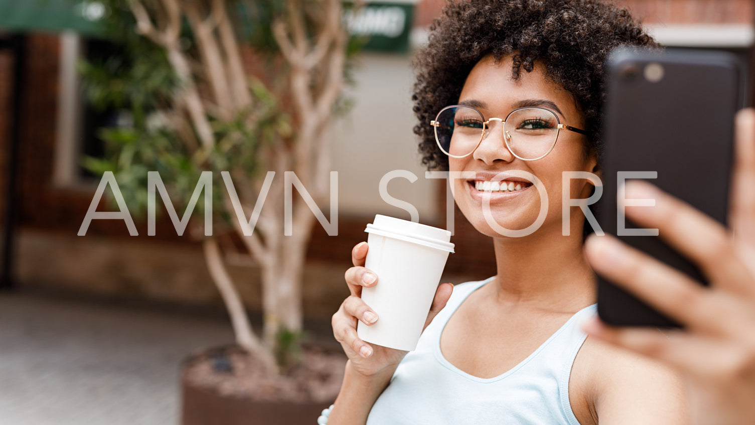 Happy girl with cup of coffee to go taking selfie	