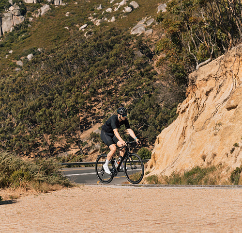 Young male on a bicycle in wild terrain on an empty road
