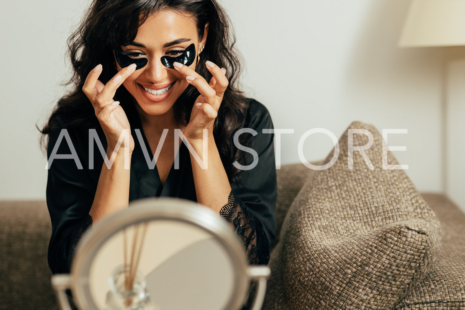 Brunette woman looking at the mirror applying black eye patches with fingers	