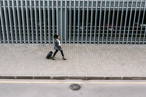 High angle view of businesswoman walking with suitcase near parking garage