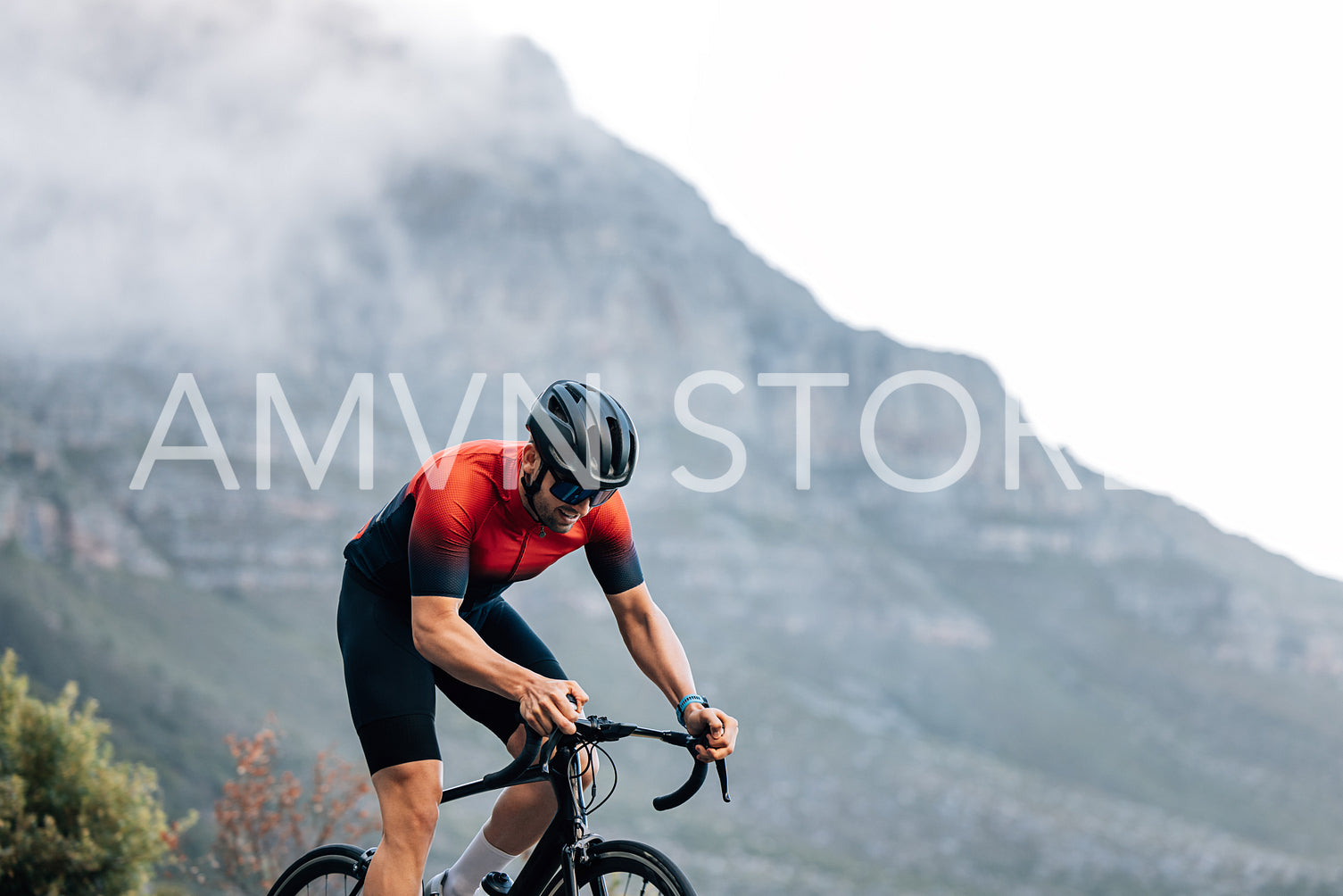 Professional rider on a bike doing intense training outdoors against the mountain with clouds