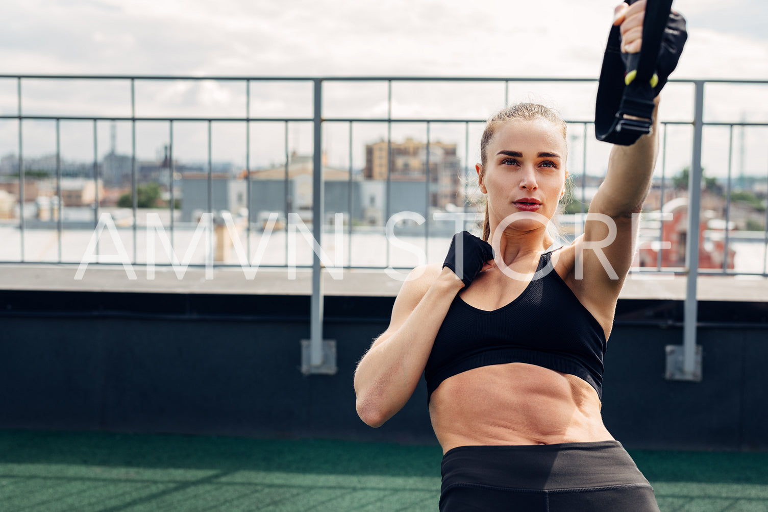 Fitness woman in sportswear exercising on rooftop. Young athlete using suspension rope for push ups.	
