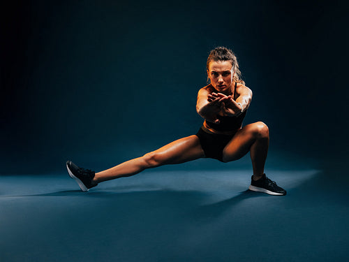 Strong woman doing warming up exercises. Muscular female stretch