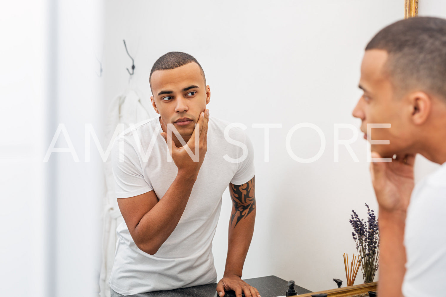 Portrait of a handsome young man examining his face in the bathroom mirror	