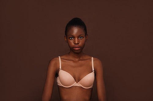 Portrait of a young woman in lingerie against brown background