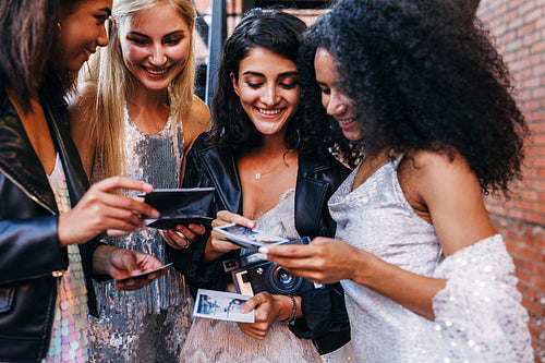 Women with instant photographs. Friends choosing frames after party.