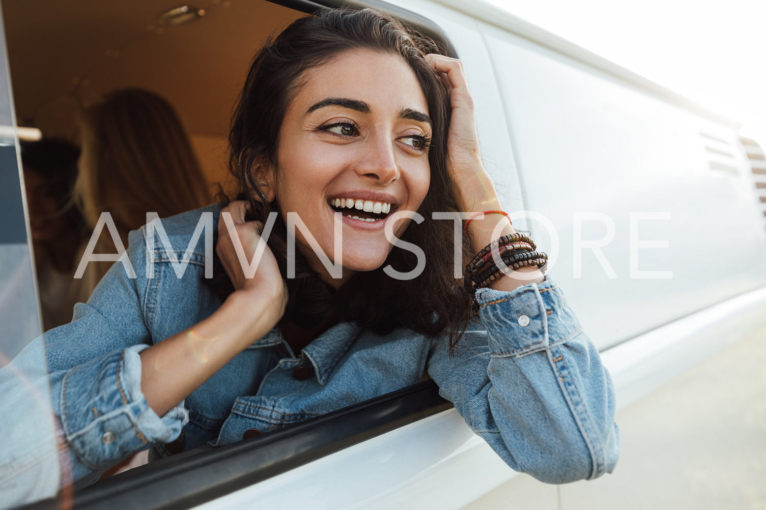 Happy woman enjoying the car ride. Beautiful young female looking out of the van.