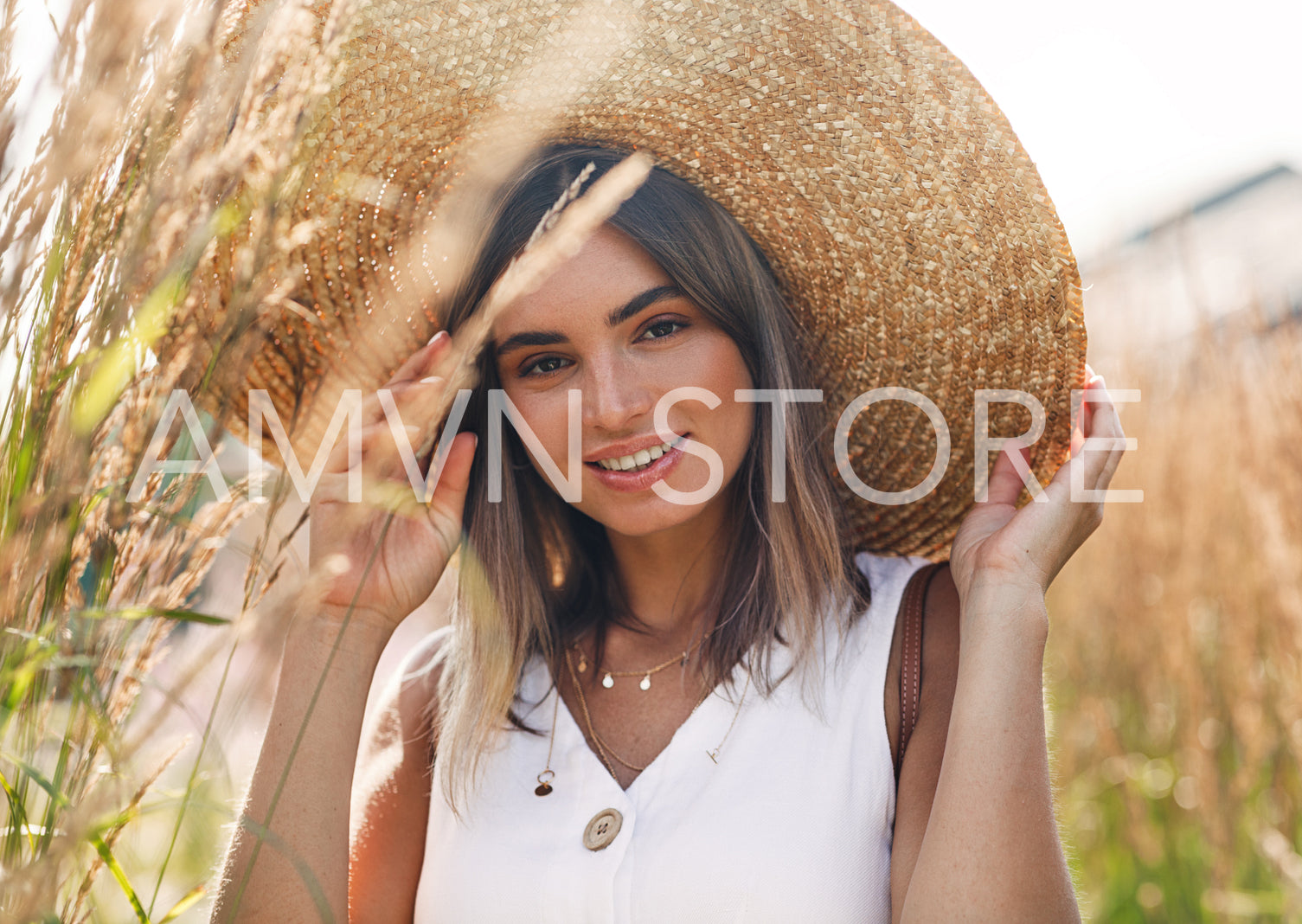 Young beautiful woman wearing a sun hat and looking at camera while standing on a field	