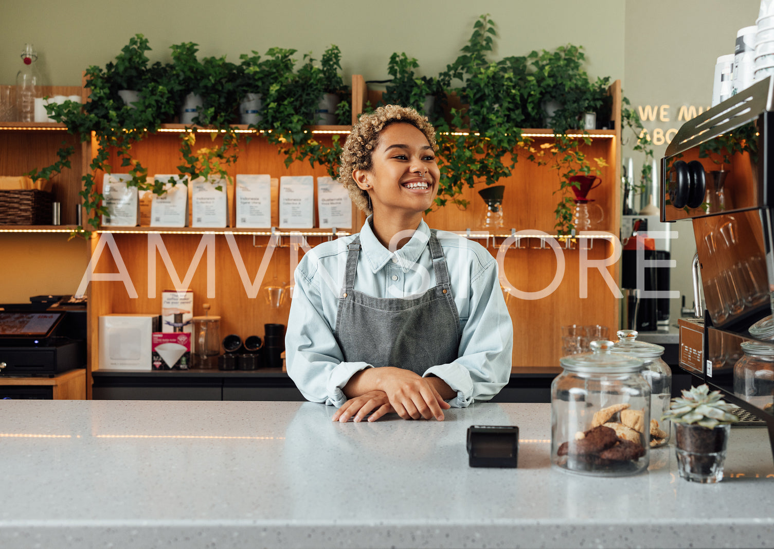 Young happy barista at the counter. Woman working as a barista standing at a cafe.