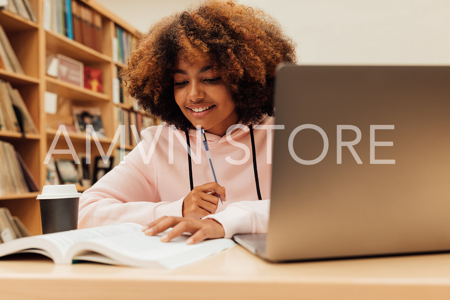 Young smiling female preparing exams while sitting in library