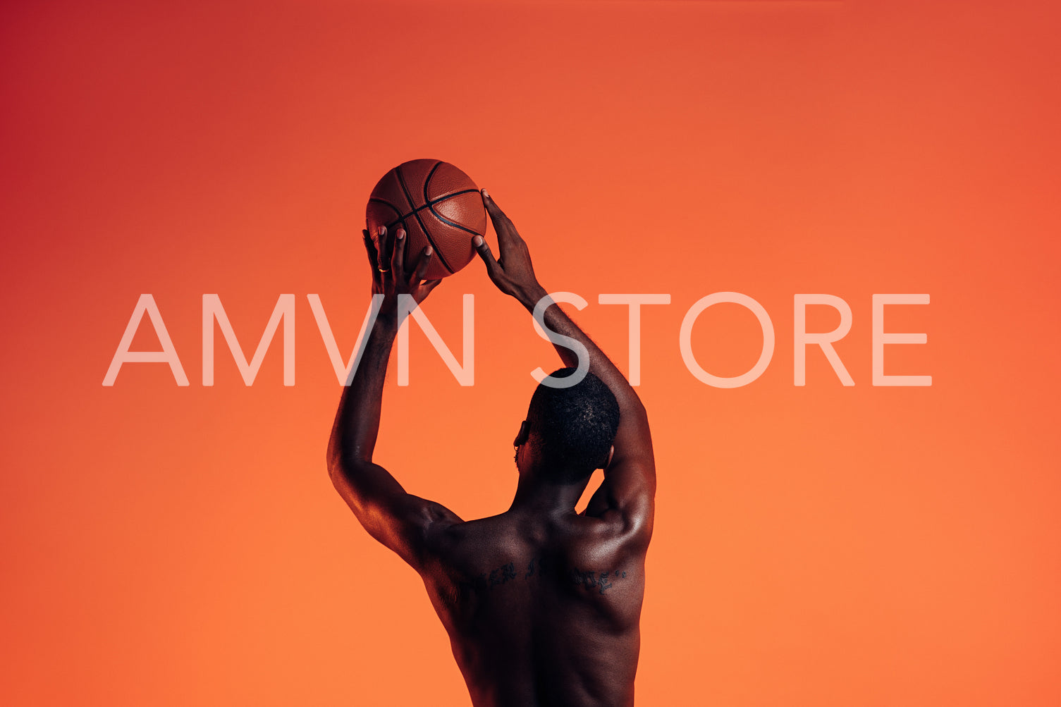 Back view of basketball player against an orange background. Young man in studio preparing to throw basket ball.