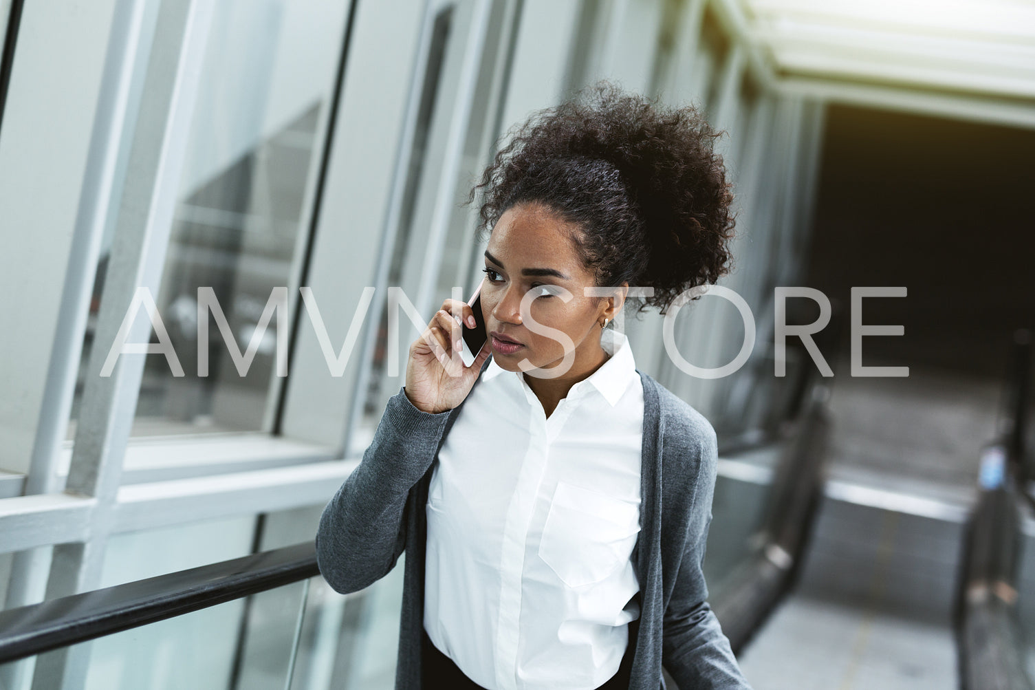 Woman making phone call while lifting up on escalator	