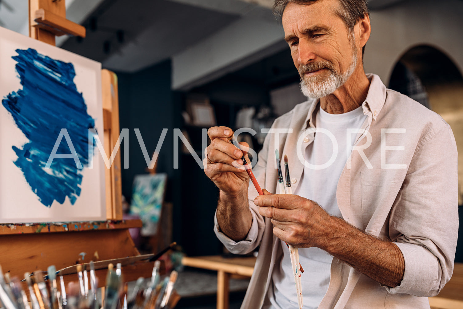 Mature painter checking brush in his studio	