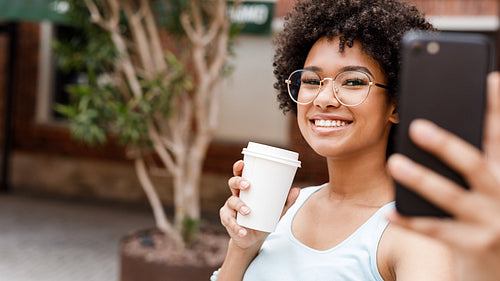 Happy girl with cup of coffee to go taking selfie