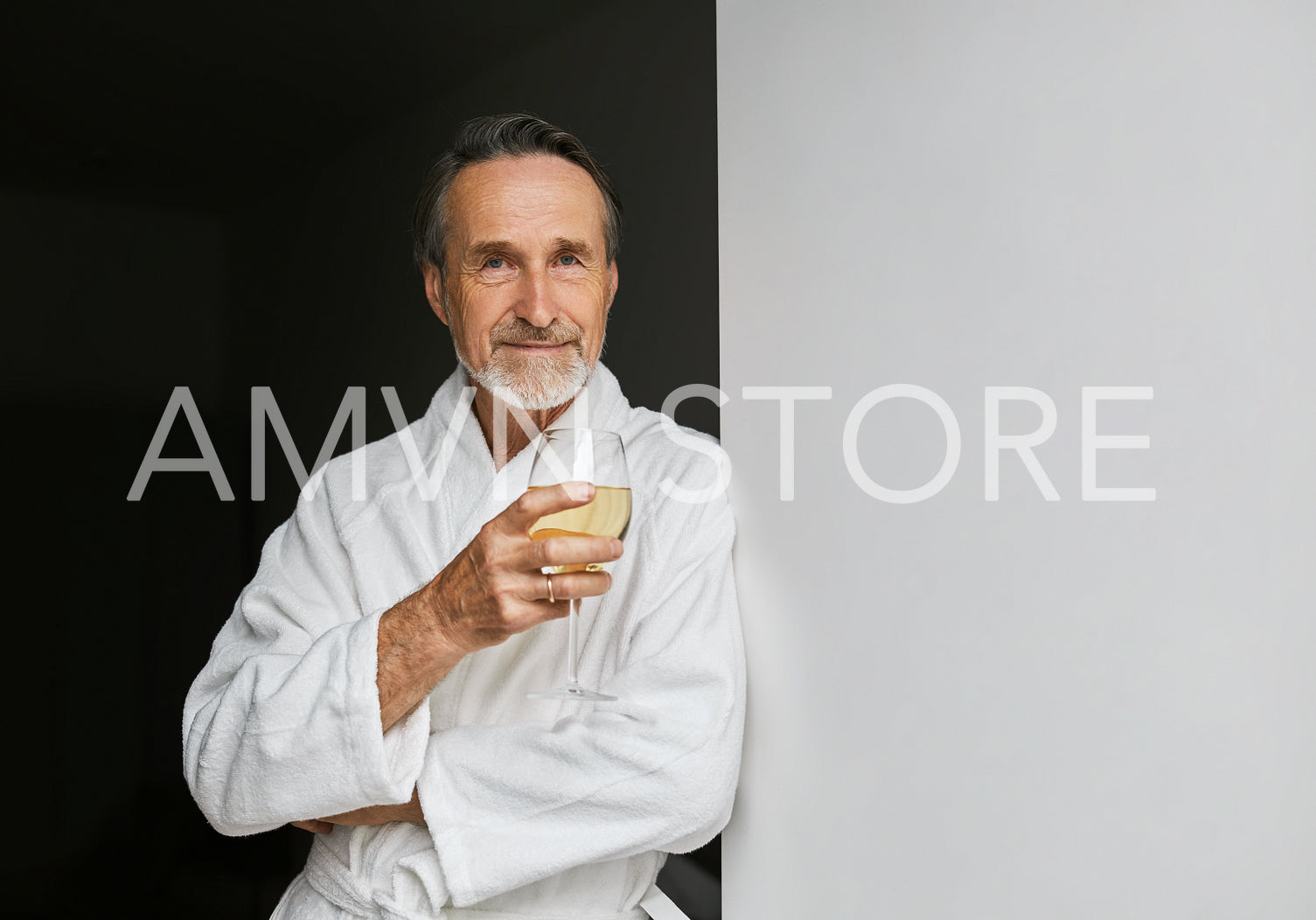 Portrait of a senior man leaning on a wall holding a glass of wine	