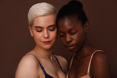 Two young women in lingerie standing with closed eyes head to head