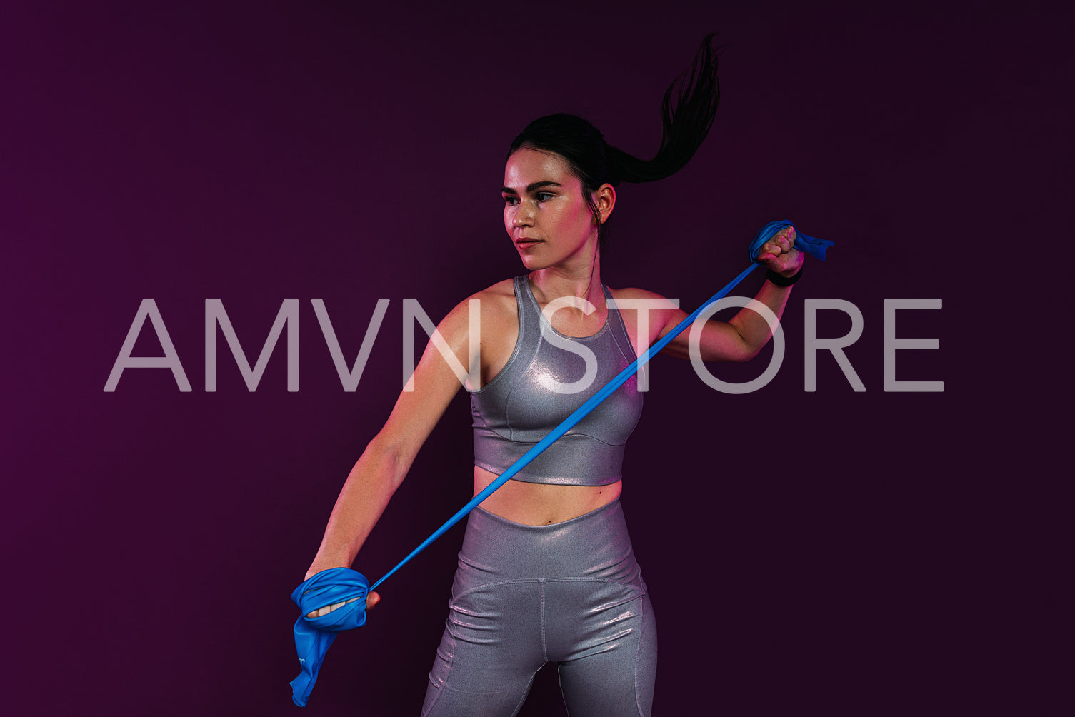 Slim woman wearing silver fitness attire exercising with resistance band