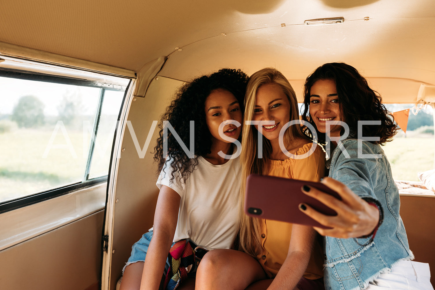 Group of female friends on a road trip taking selfie in a camper van