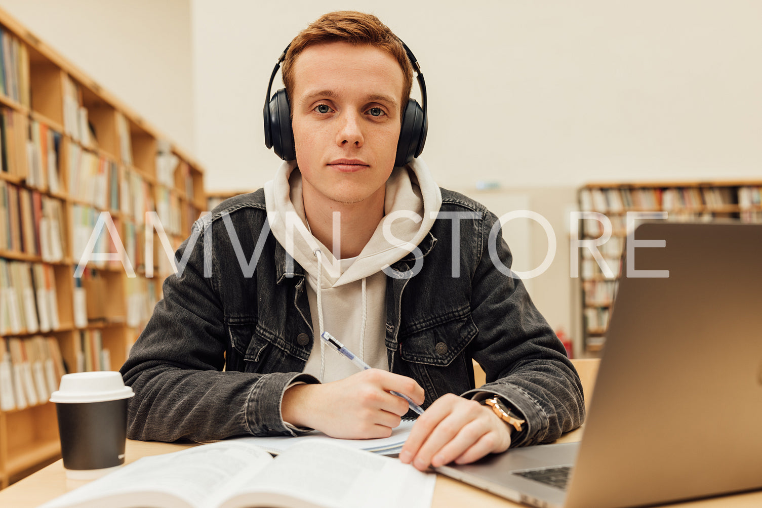 Handsome male student in a university library. Young man studying on school assignment.