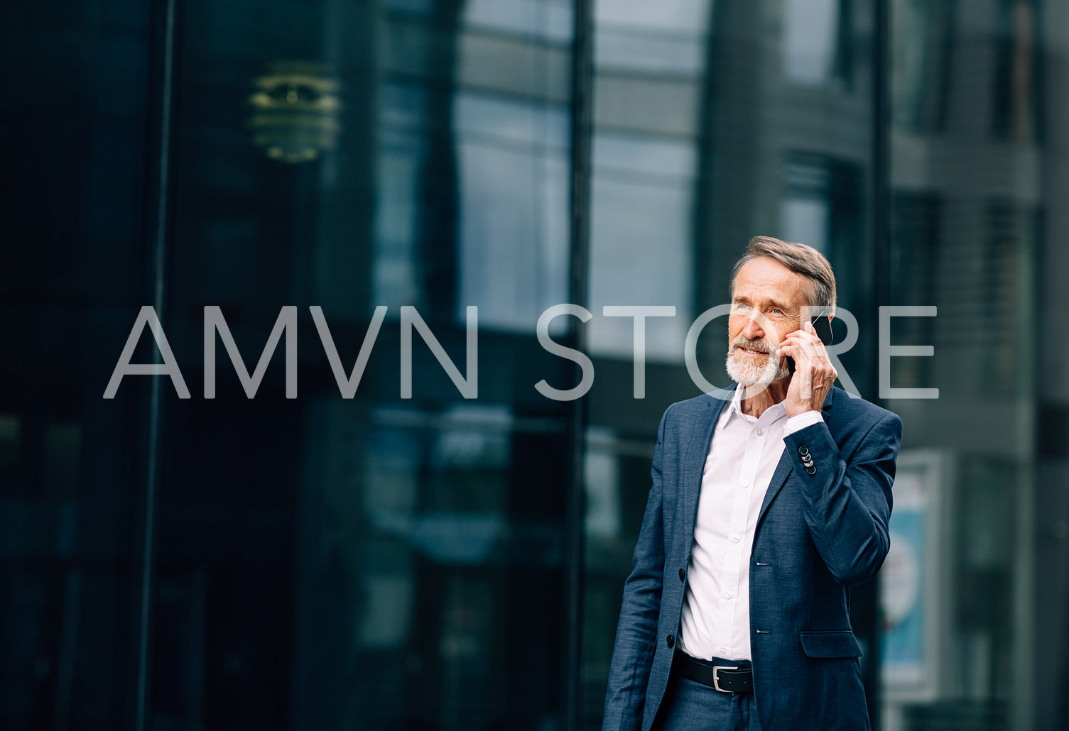 Senior businessman walking at office building and talking on cell phone