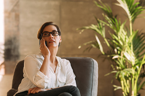 Middle-aged businesswoman in eyeglasses talking on mobile phone