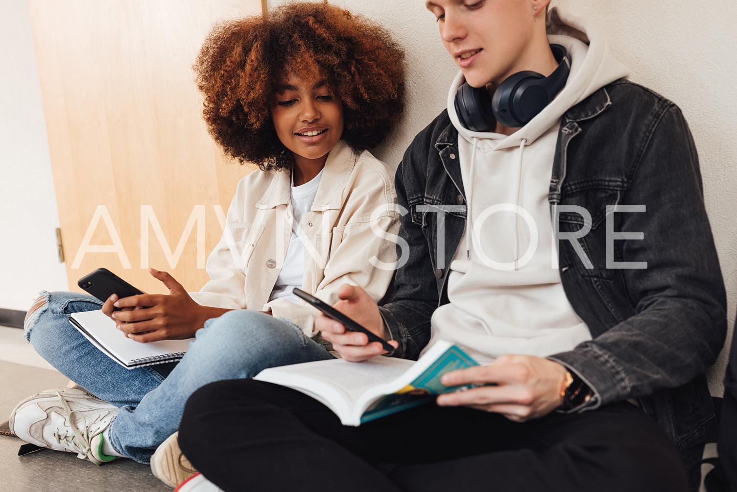 Classmates sitting together with smartphones and preparing their assignments