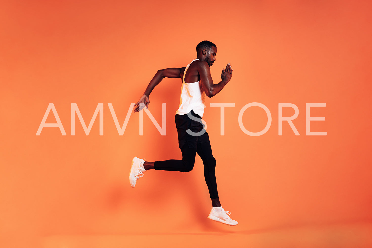 Male athlete wearing sports clothes running against an orange background