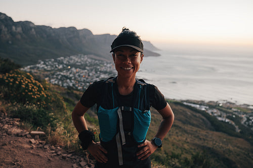 Woman hiker in sports wear looking at camera at sunset