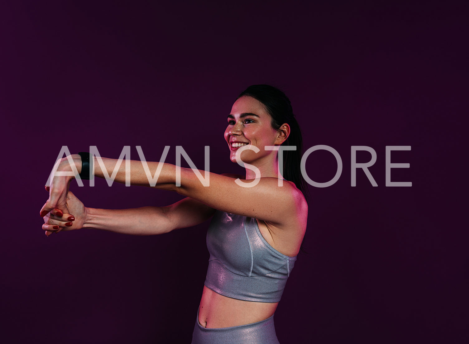 Smiling female stretching and flexing her hands over magenta background in studio