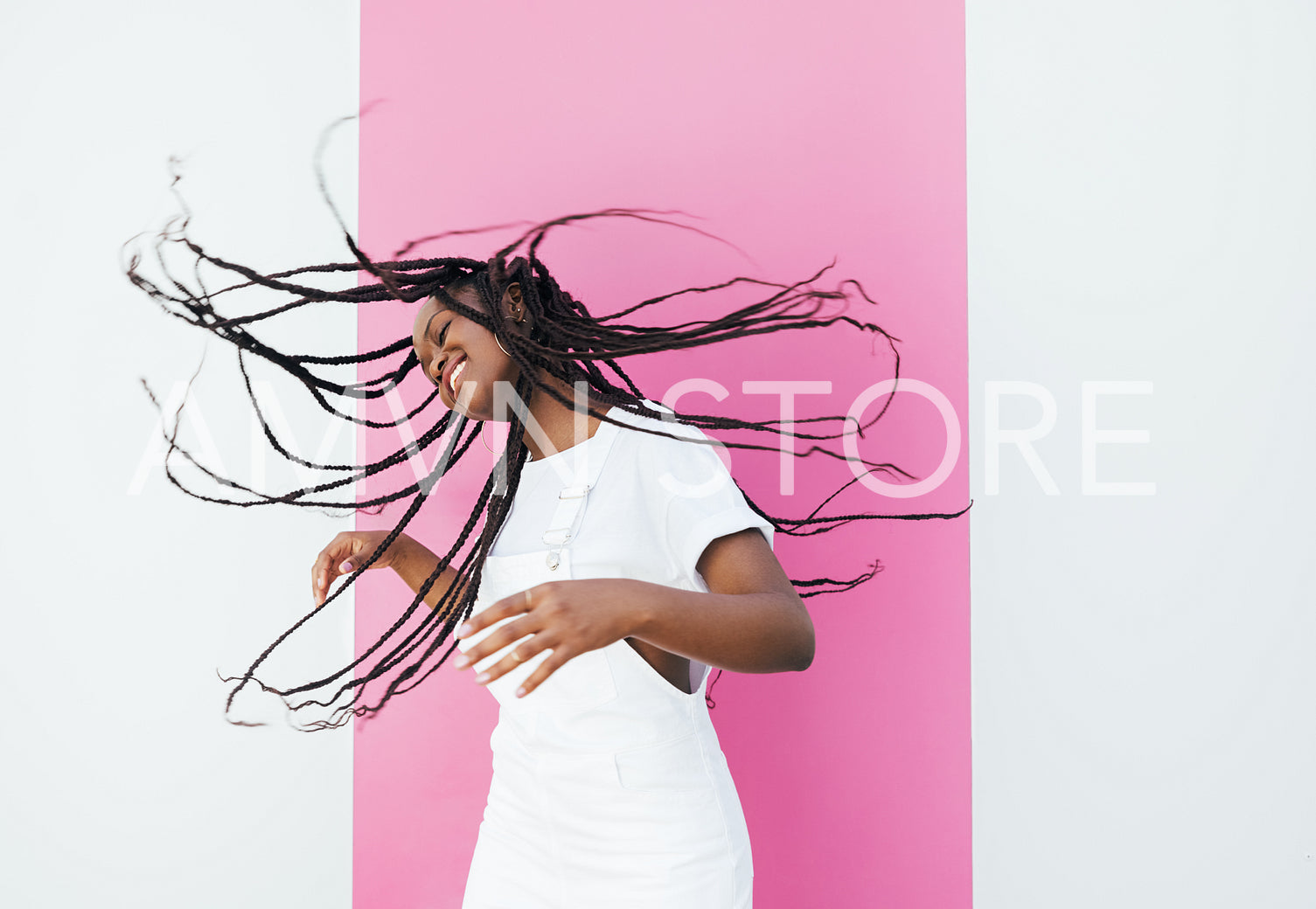 Smiling woman flying her hair in the air at the pink wall outdoors