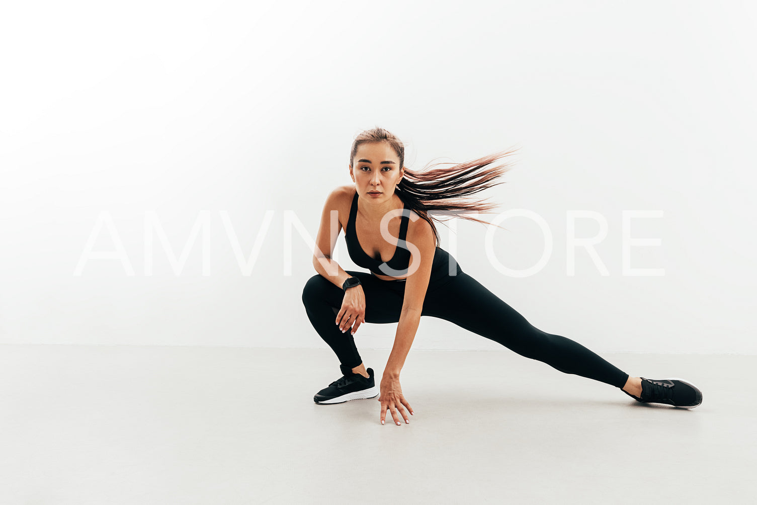 Asian woman warming up before workout against white wall