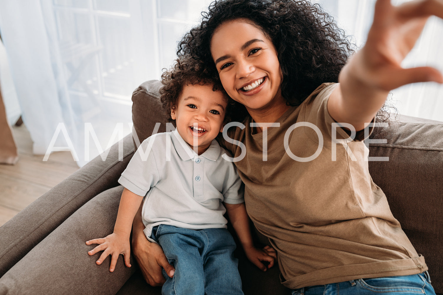 Young woman and her little son taking selfie. Happy mother with her kid sitting on a sofa.	