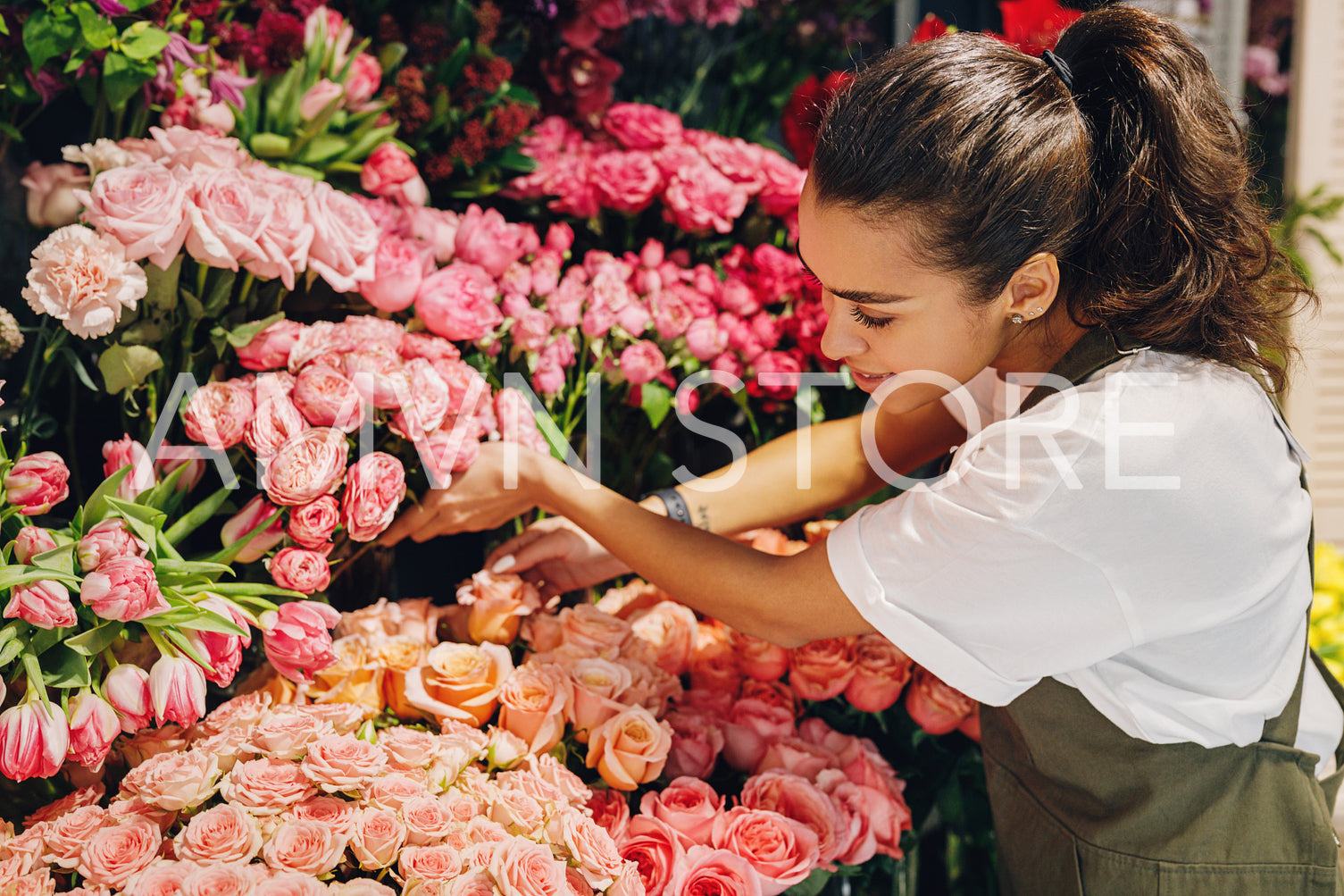 Young woman working in a flower shop. Female florist choosing flowers.	