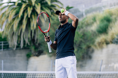 Young man with a tennis racket and tennis ball relaxing during a match