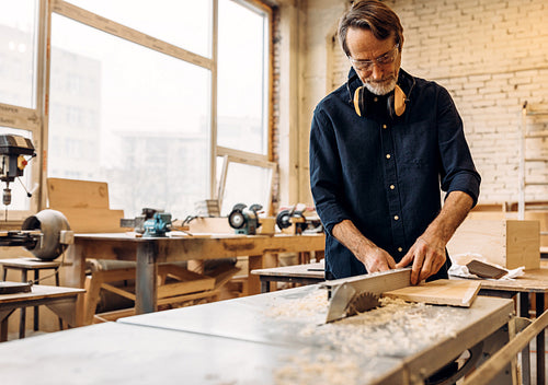 Male works in carpentry. Man adjusting saw machine.