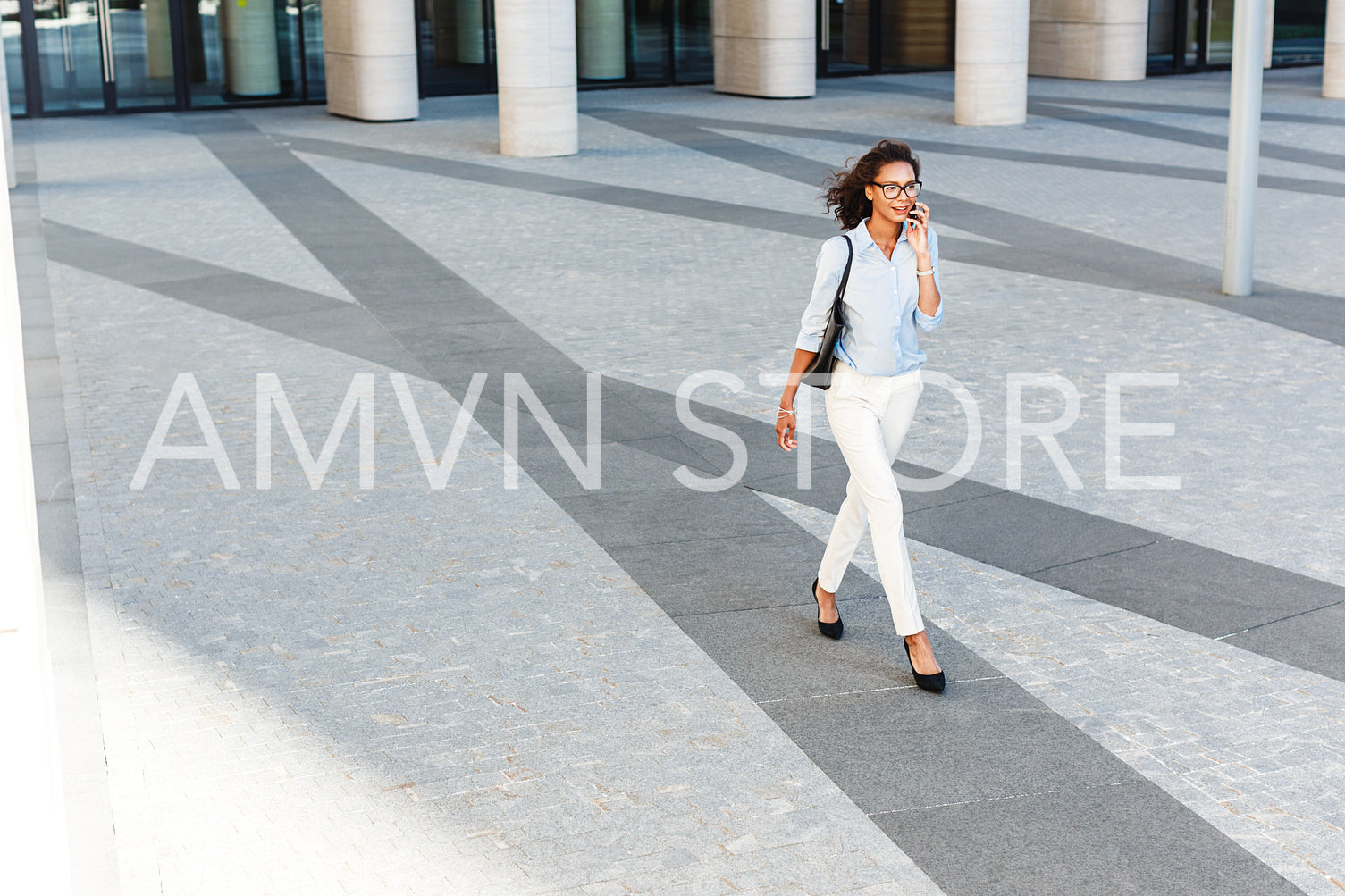 High angle view of a young woman carrying bag on shoulder and walking on city street