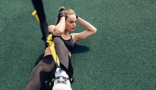 High angle view of woman athlete doing abdominal exercises using suspension straps