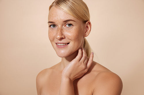 Blond woman looking at camera touching her neck