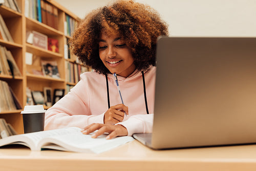 Young smiling female preparing exams while sitting in library