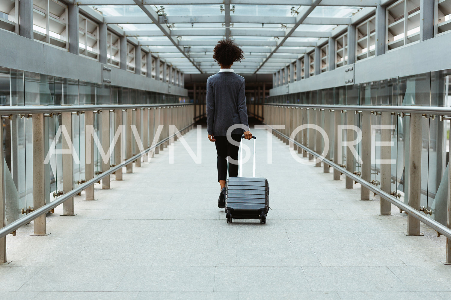 Back view of businesswoman walking in terminal with luggage	