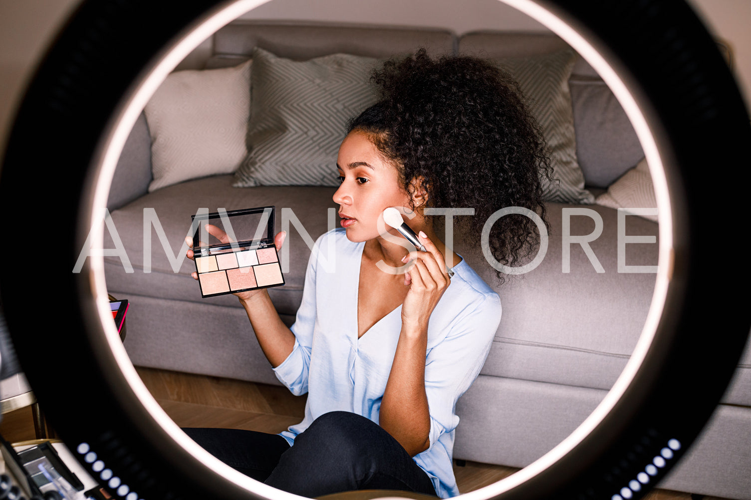 Female vlogger recording a makeup tutorial, applying cosmetics with brush	