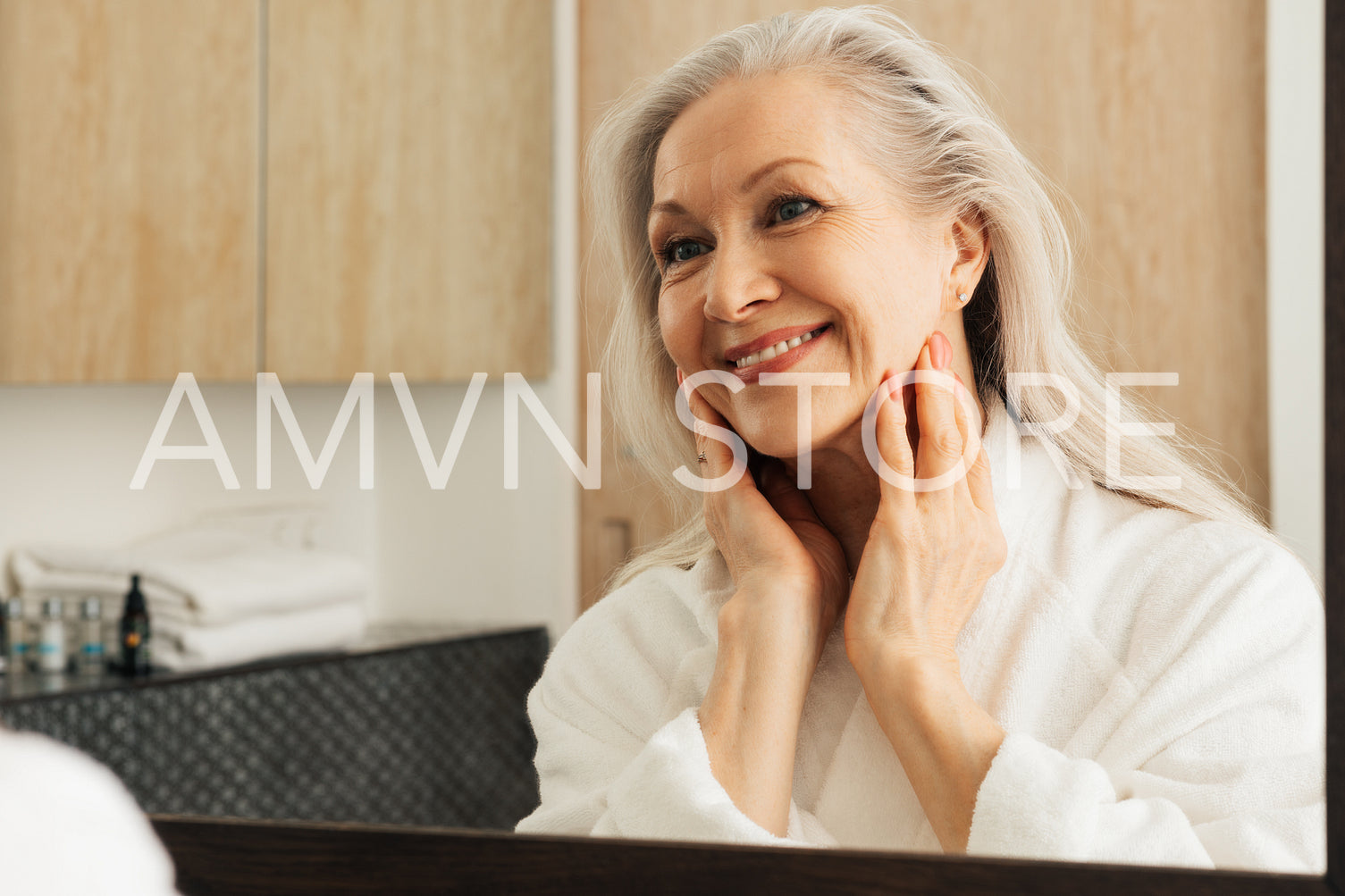 Cheerful aged female looking at her reflection in the morning