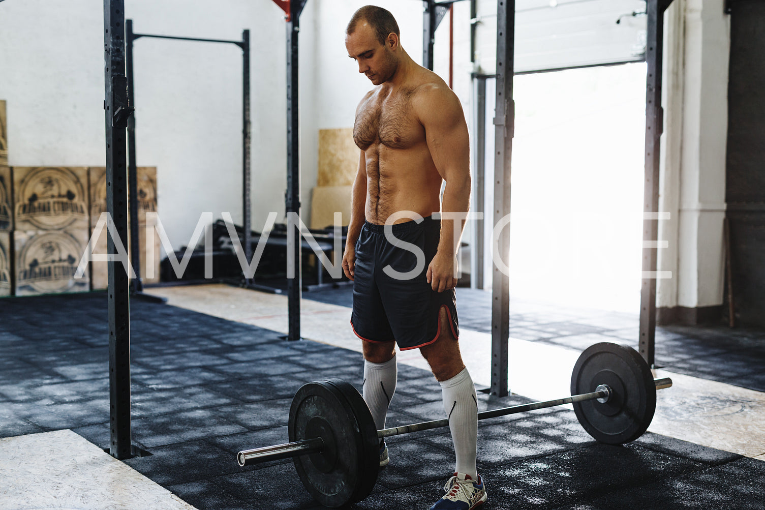 Confident young man standing with barbell at fitness center