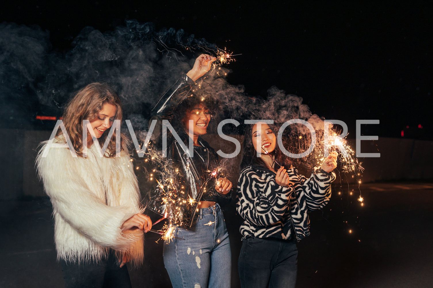 Three happy girls walking at night with sparklers and having fun	